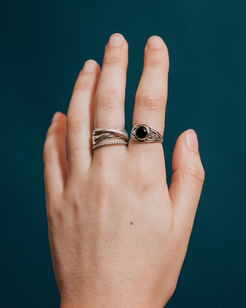 Hand wearing two rings with a dark blue background